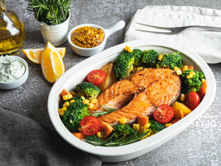 fried baked fish steak salmon, trout with broccoli and carrots, corn in pot