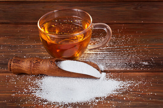 Cup of tea and scoop of sorbitol on a wooden background. Sweeteners and diet concept.