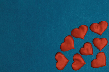 Obraz premium Red textile hearts in corner on blue cardboard background. Valentines Day concept, copy space, flat lay.