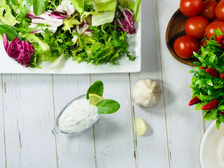 Garlic sauce in a gravy boat on the table. Cooking a dietary dinner. Salad ingredients.