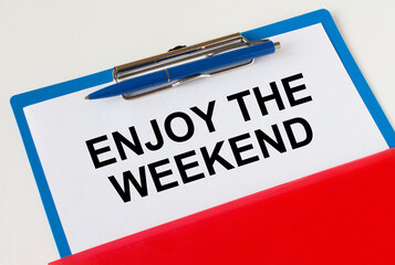 Obraz premium Clipboard with text Enjoy The Weekend blue pen and red folder