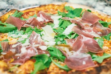 Pizza from the oven. Oven-baked pizza with Italian ham and arugula close up