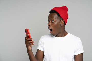 Surprised afro young man makes big eyes opens mouth widely, shocked with unprecedentedly low...