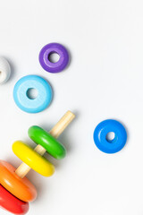 Multi-colored wooden children's toy pyramid on white background. Eco friendly toy, plastic free. Toy for babies and toddlers. Natural wood toys. Colors of rainbow. Flat lay top view copy space