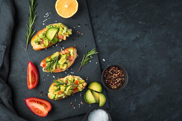 Three fresh guacamole sandwiches and tomatoes on a flat platter on a black concrete table. Top view, with space to copy. The concept of proper nutrition.