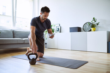 Man setting up online workout app at home - Powered by Adobe