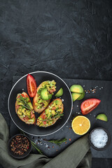 Sandwiches with guacamole on a plate, lemon and rosemary on a black background. Top view, vertical orientation with space to copy. The concept of healthy eating.