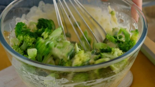 Close-up. Whisk the ingredients in a glass bowl to make broccoli and cheese frittat in a baking dish. Italian breakfast. Baked chopped omelet with vegetables and broccoli. Healthy breakfast.