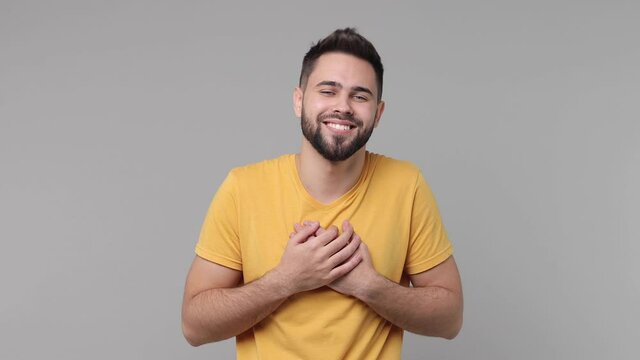 Amazed smiling bearded young man 20s years old in yellow casual basic t-shirt isolated on grey color background studio. People lifestyle concept. Point hands on himself ask who me put palms on chest