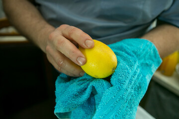 The process of making limoncello lemon liqueur at home. A man wipe washed lemons with a dry clean...