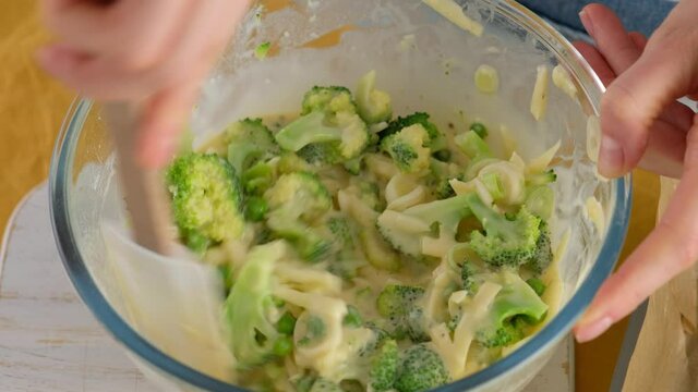 Close-up. Stir the ingredients in a glass bowl to make broccoli and cheese frittat in a baking dish. Italian breakfast. Baked chopped omelet with vegetables and broccoli. Healthy breakfast.