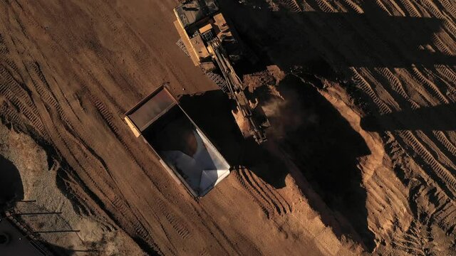 Aerial above excavator loading a dump truck with dirt on a construction site