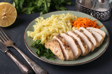 Baked chicken fillet, pasta and fresh carrots - a delicious and healthy breakfast. Close-up
