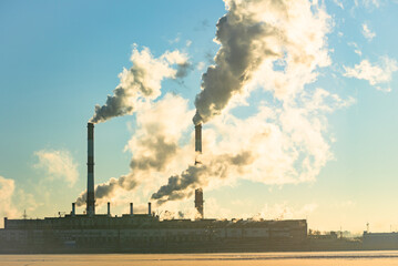 Factory pipe polluting air, smoke from chimneys against sun, environmental problems, ecological theme, industry scene