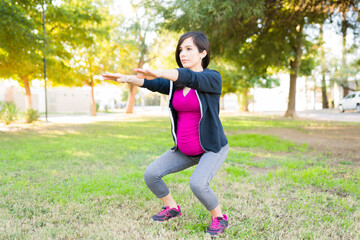 Fit and sporty pregnant woman squatting outdoors