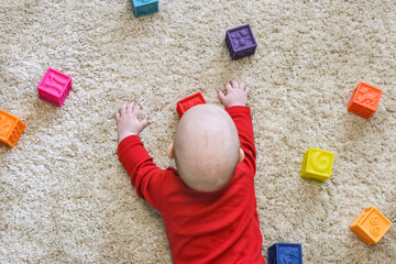 A small child plays with tactile blocks on a beige carpet. Sensory development. Children Developing silicone cubes. Educational Baby Toys 6 Months & Up with Numbers, Shapes, Animals & Textures
