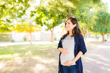 Cheerful pregnant woman posing outdoors