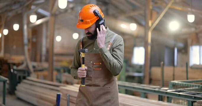 Joyful carpentry worker in safety hard hat having a break, singing and dancing at the manufacturing. Employee having fun at the factory