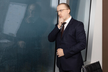 Portrait of tired manager near wet panoramic skyscraper window