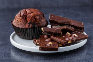 Chocolate cupcake with icing and chocolate bar in Dark lighting,Homemade delicious chocolate muffin on wooden background close-up