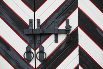 Old rustic black and white fortress wooden gates locked. Abstract modern pattern in wood constructions.