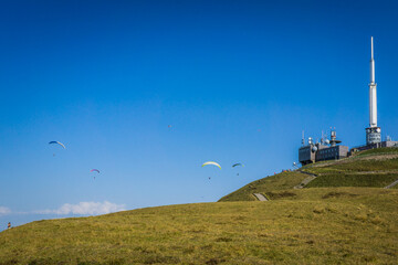 Fototapeta na wymiar Paragliders flying around the Puy de Dome meteorological station in Auvergne, France