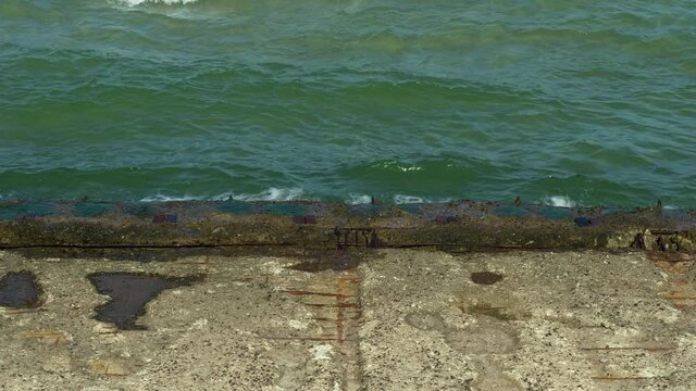 Waves of the Baltic Sea washing out an old reinforced concrete construction of an abandoned sea bridge ruin which belongs to the Colossus of Prora in Binz, Germany on a summer day at the beach