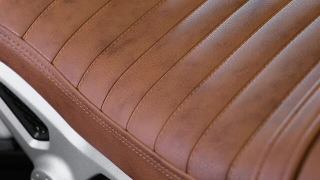 The brown leather seat of the new motorcycle with stitching. Closeup cinematic 4k shot