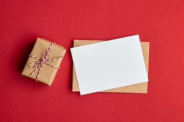 Greeting card mockup with envelope and gift box on red paper background