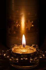 Burning tea candle with Christmas snowflake motif.
