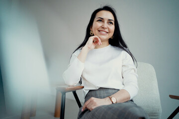 break during work. smiling sitting on the couch in a modern office. an experienced manager in a bank is a confident young woman with a brunette European appearance. copy space.