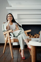 smart businesswoman working sitting on a chair and smiling. Stylish office, dressed in a business suit and shoes. stylish interior background fireplace