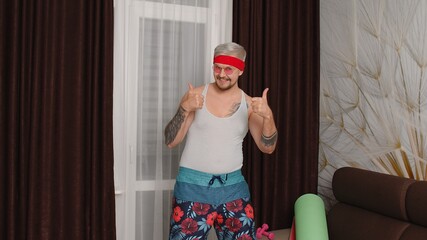 Hello or bye. Sportsman retro guy in funny sport clothes showing thumbs up, smiling at home. Portrait of fat bearded man hipster of 80s. Joke, comical, meme, parody, humor