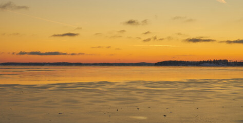 The coast of the sea in ice and in the snow at sunset.