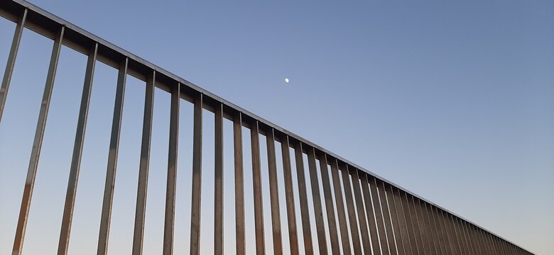 Luna en la lejan&iacute;a con un pasamanos en primer plano