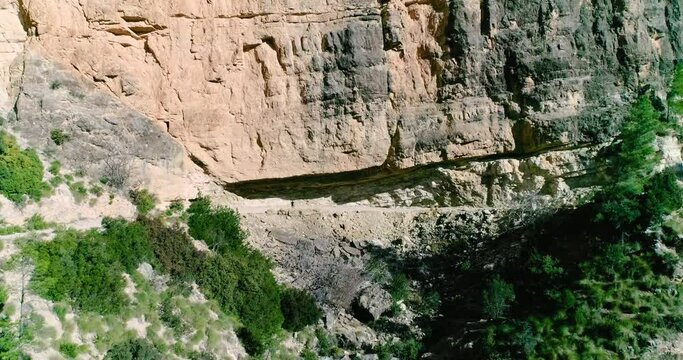 Gran muro de piedra de monta&ntilde;a y sendero colgado en pared y senderista bajo la piedra
