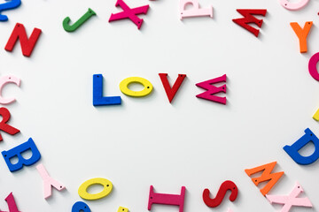 Love - a word of multicolored letters on a white table background, English or American Flat Lay alphabet. Valentine's Day.