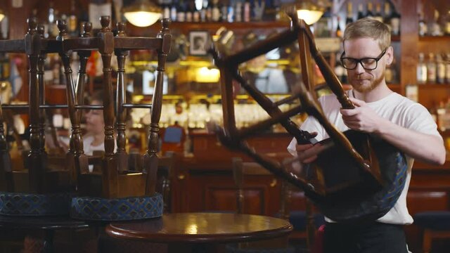 Waiters in modern pub putting furniture down preparing for opening