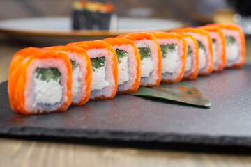 Sushi roll (Philadelphia) with salmon, smoked eel, avocado, cream cheese on black background. Sushi menu. Japanese food.