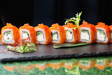 Sushi roll (Philadelphia) with salmon, smoked eel, avocado, cream cheese on black background. Sushi menu. Japanese food.