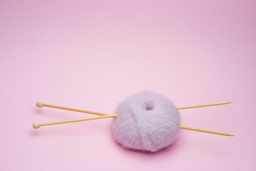 Knitting yarn balls and knitting needles on pink background