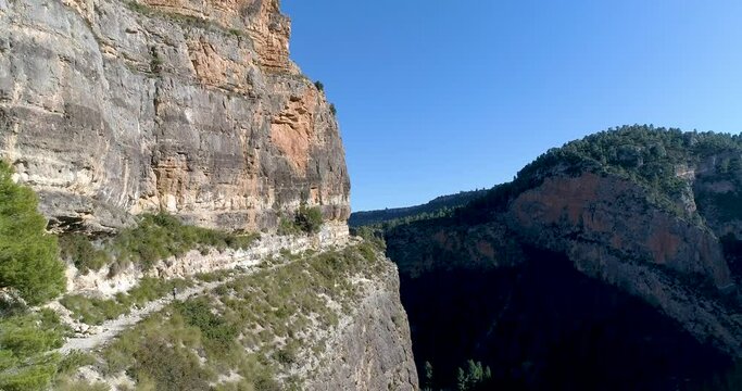 Adolescente senderista caminado en senda en mitad de barranco profundo