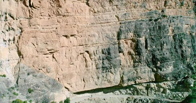 dron vuela por pared de piedra y mujer senderista camina bajo la piedra
