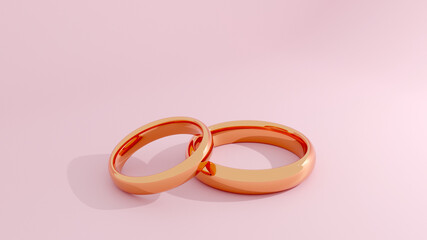 Two gold wedding rings with pink background