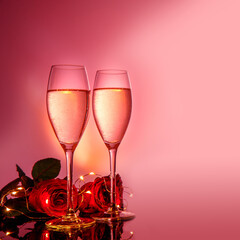 Champagne glasses, red roses in front of pink beige background. Valentines day holiday composition. Birthday, Women's, Wedding Day concept.