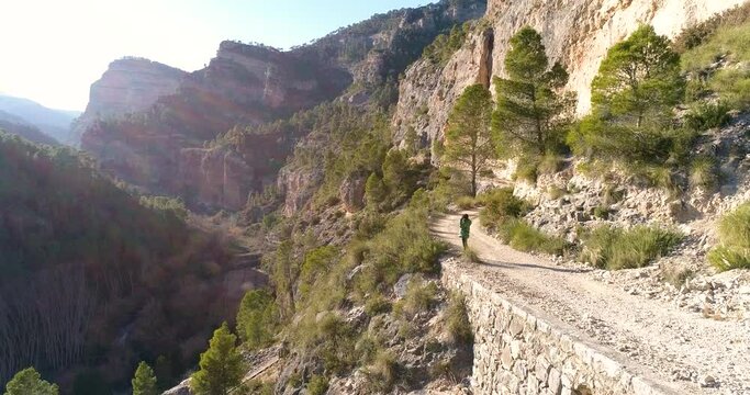 dron vuela sobre mujer mirando por prism&aacute;ticos en sendero de alta monta&ntilde;a