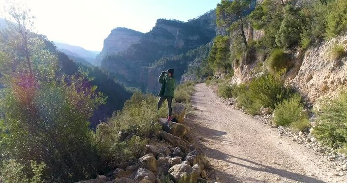 dron vuela hacia mujer madura mirando por catalejos con abrigo y gorro de invierno