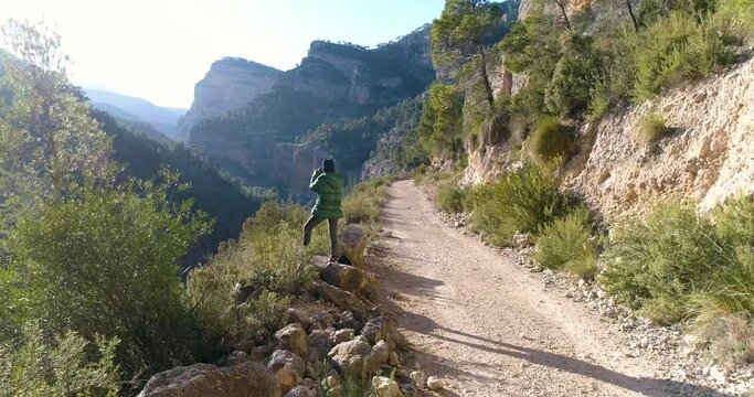 dron se acerca a mujer mirando por binoculares a valle profundo