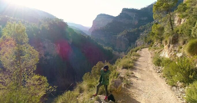 Mujer senior observa paisaje con prism&aacute;ticos en valle profundo y dron orbita