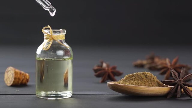 Glass bottle of anise essential oil with anise star and powder, spice oil concept, ( Pimpinella anisum ) , oil dripping